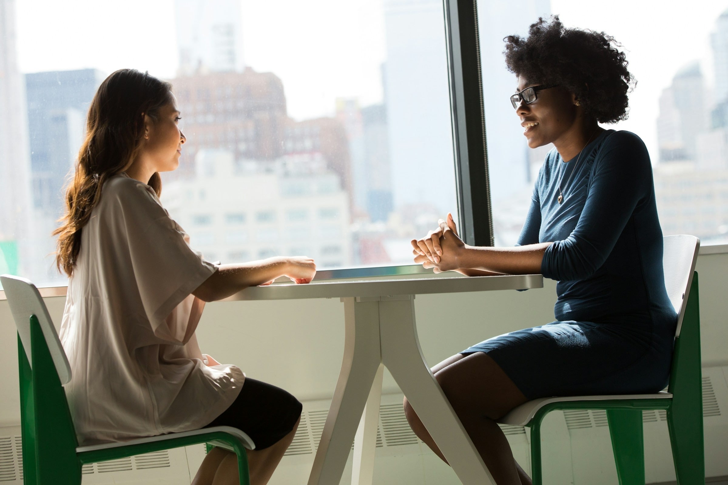 Two people in a quiet consultation at a window-side table