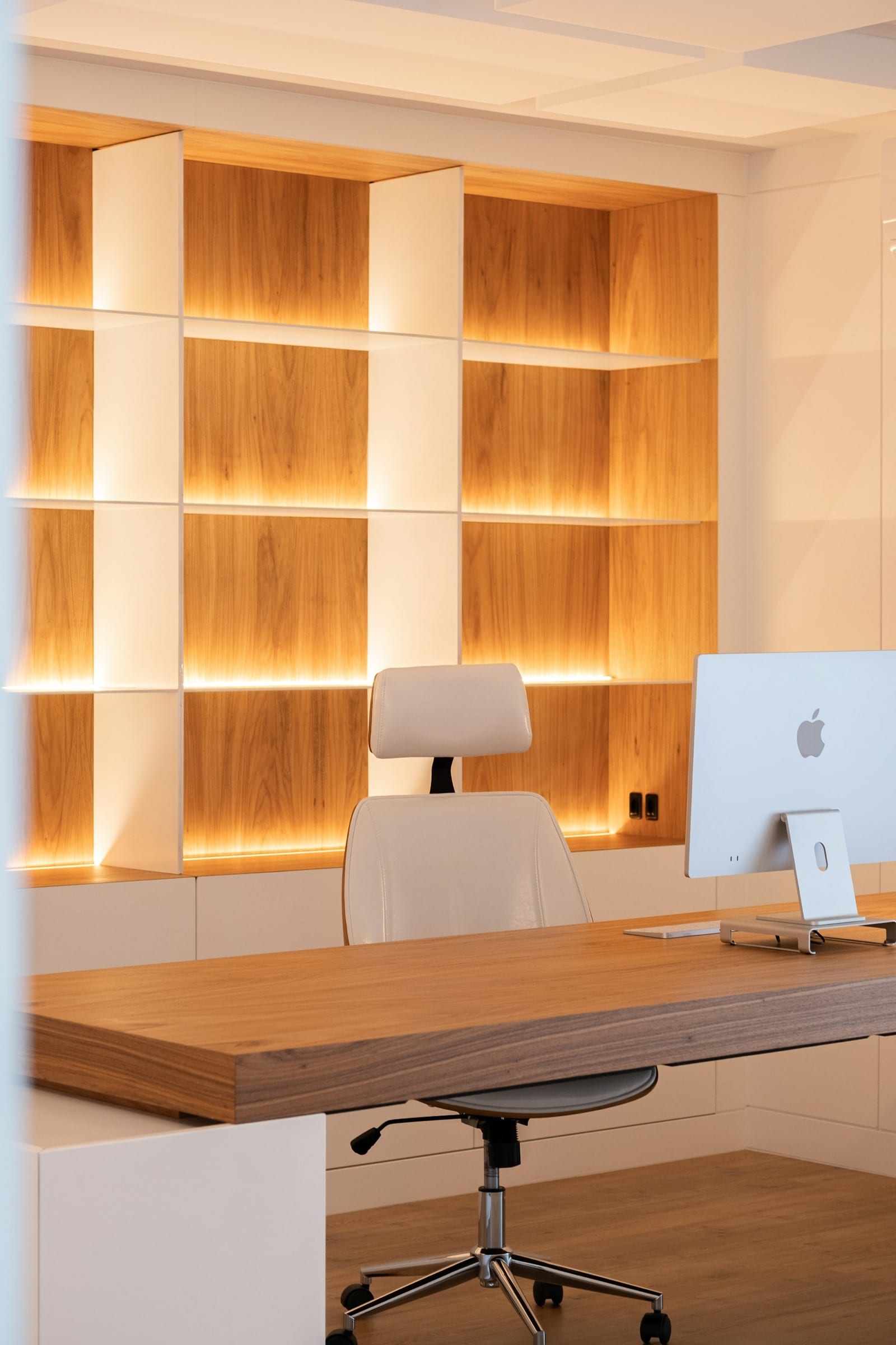 Warm wood-paneled private office with a desk and lit shelving