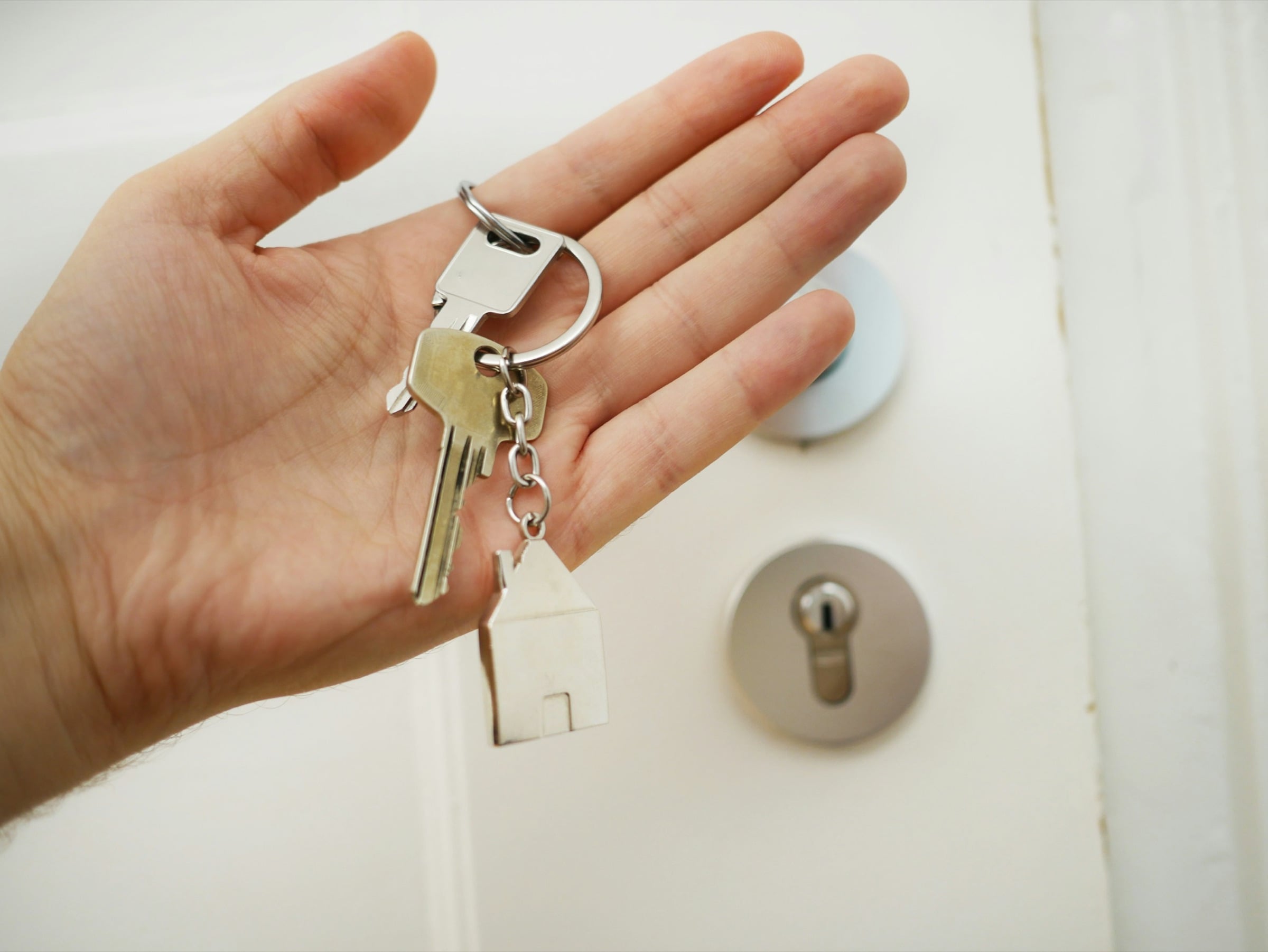 Hand holding house keys up to a front door lock