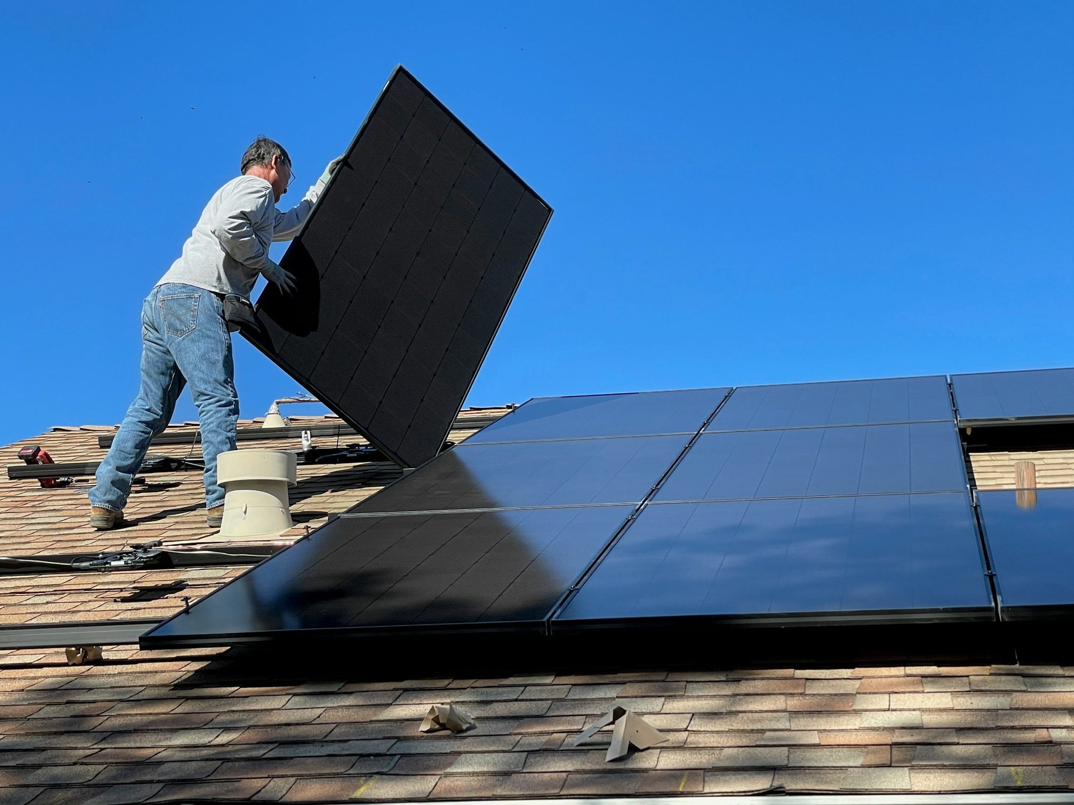 Installer setting a solar panel into place on a rooftop