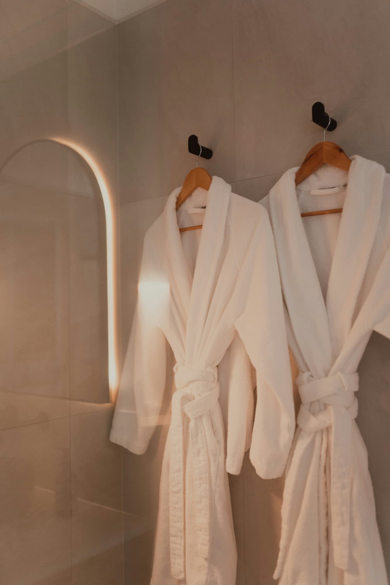 Two soft robes hanging in a warm, quiet corner of the spa