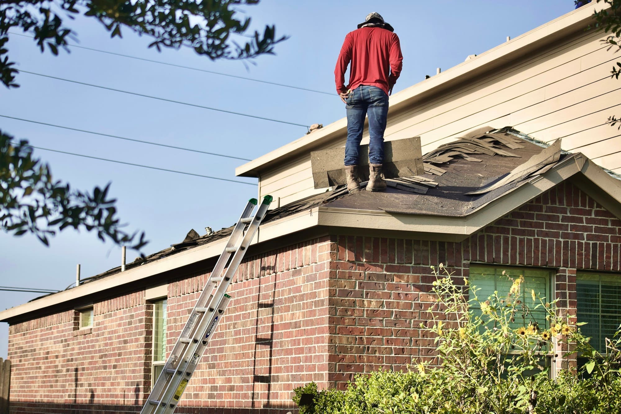 A roofer inspecting a section of roof after storm damage